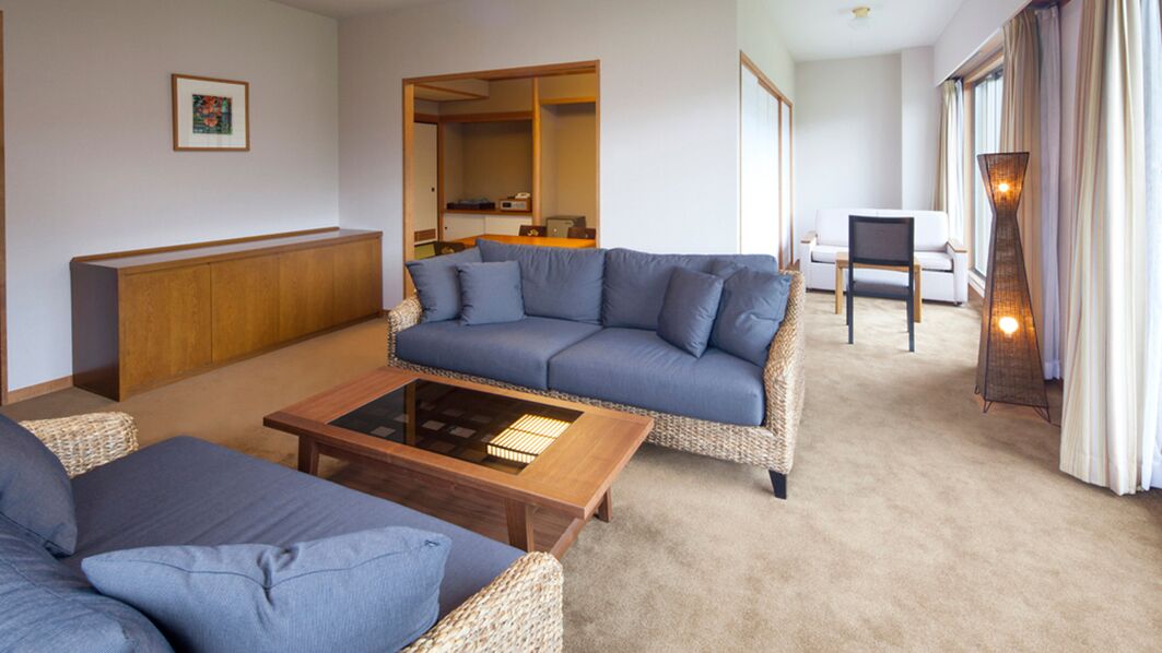 A living room with a sofa, a coffee table, and a dining area with a cabinet.