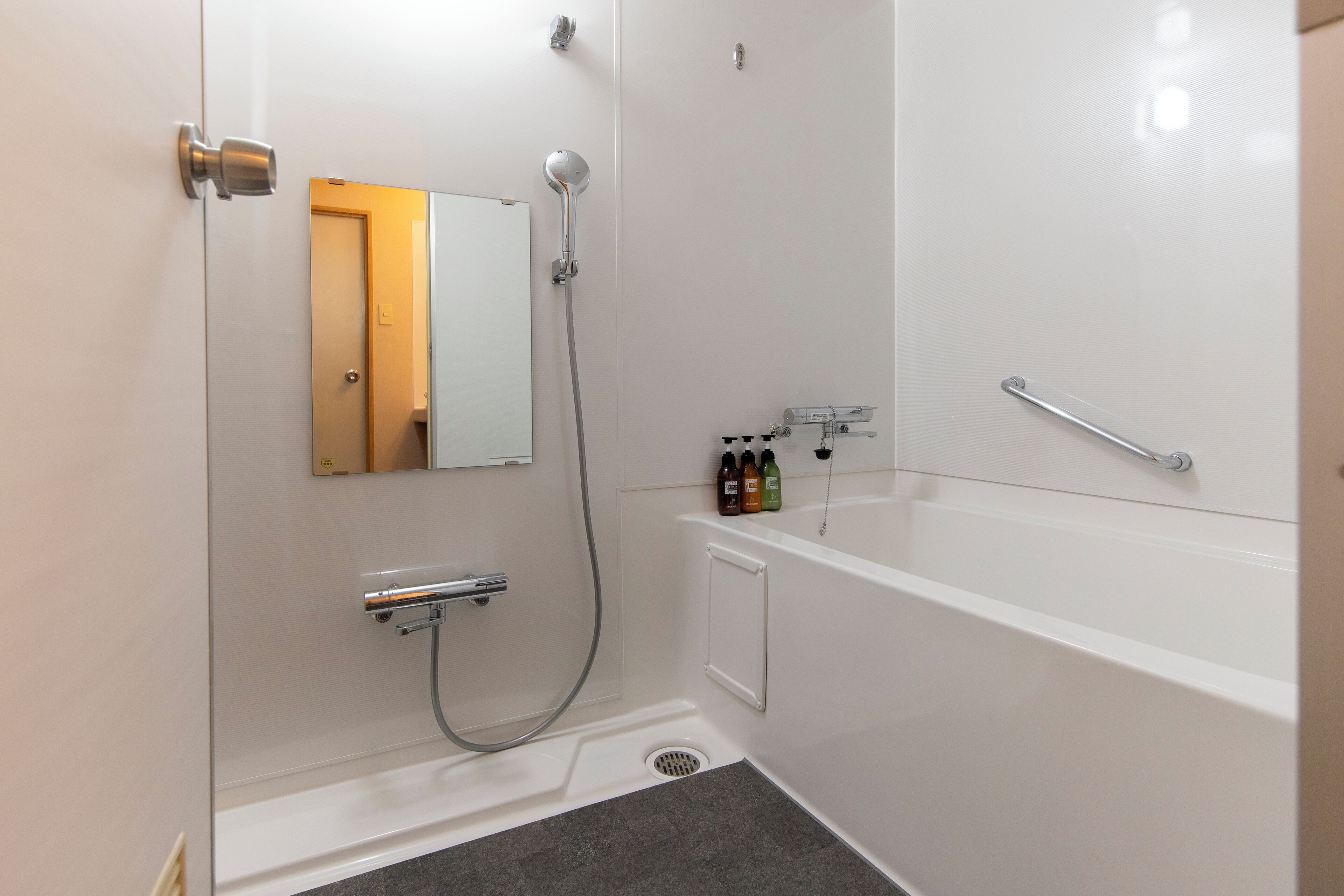 Een moderne badkamer met een douche, een bad, een toilet en een spiegel.