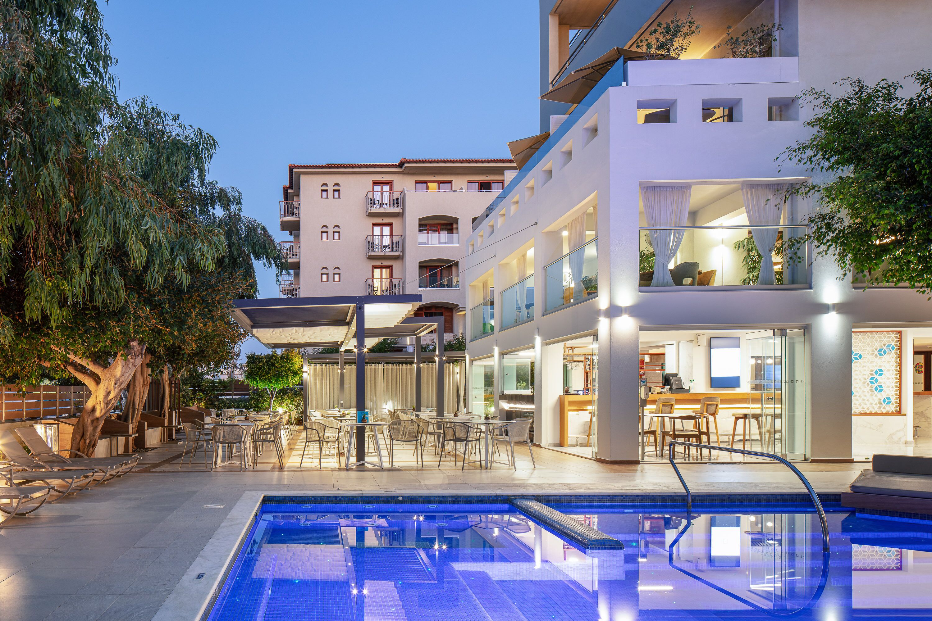 Un hotel moderno con piscina, area salotto esterna e sala da pranzo.