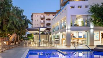 Un hotel moderno con piscina, area salotto esterna e sala da pranzo.