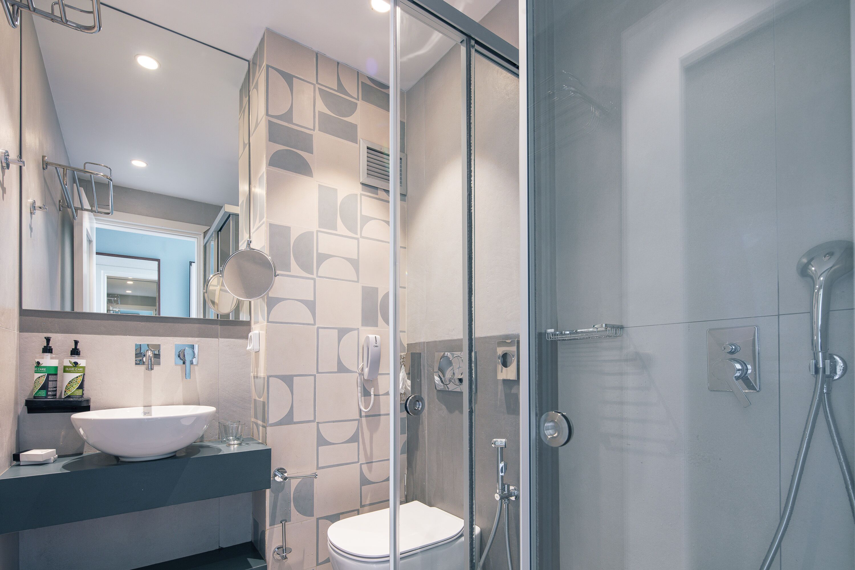 Une salle de bain moderne avec une douche à parois de verre, un lavabo blanc et un miroir au-dessus du lavabo.