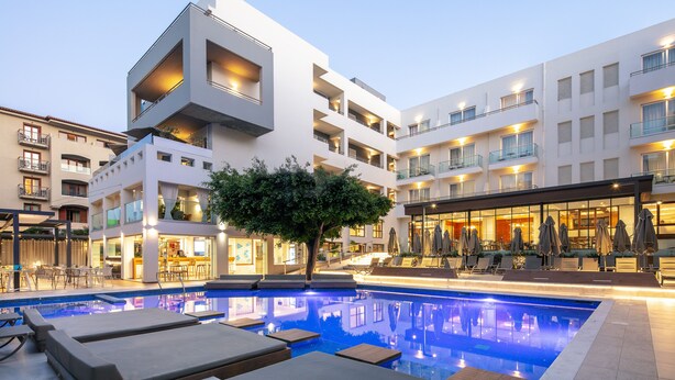 A modern hotel with a swimming pool, outdoor seating, and a bar area. - Atrium Ambiance Hotel (Rethymno)