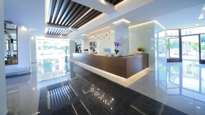 A modern reception area with a marble reception desk, large windows, and a clean, polished floor. - Atrium Ambiance Hotel (Rethymno)