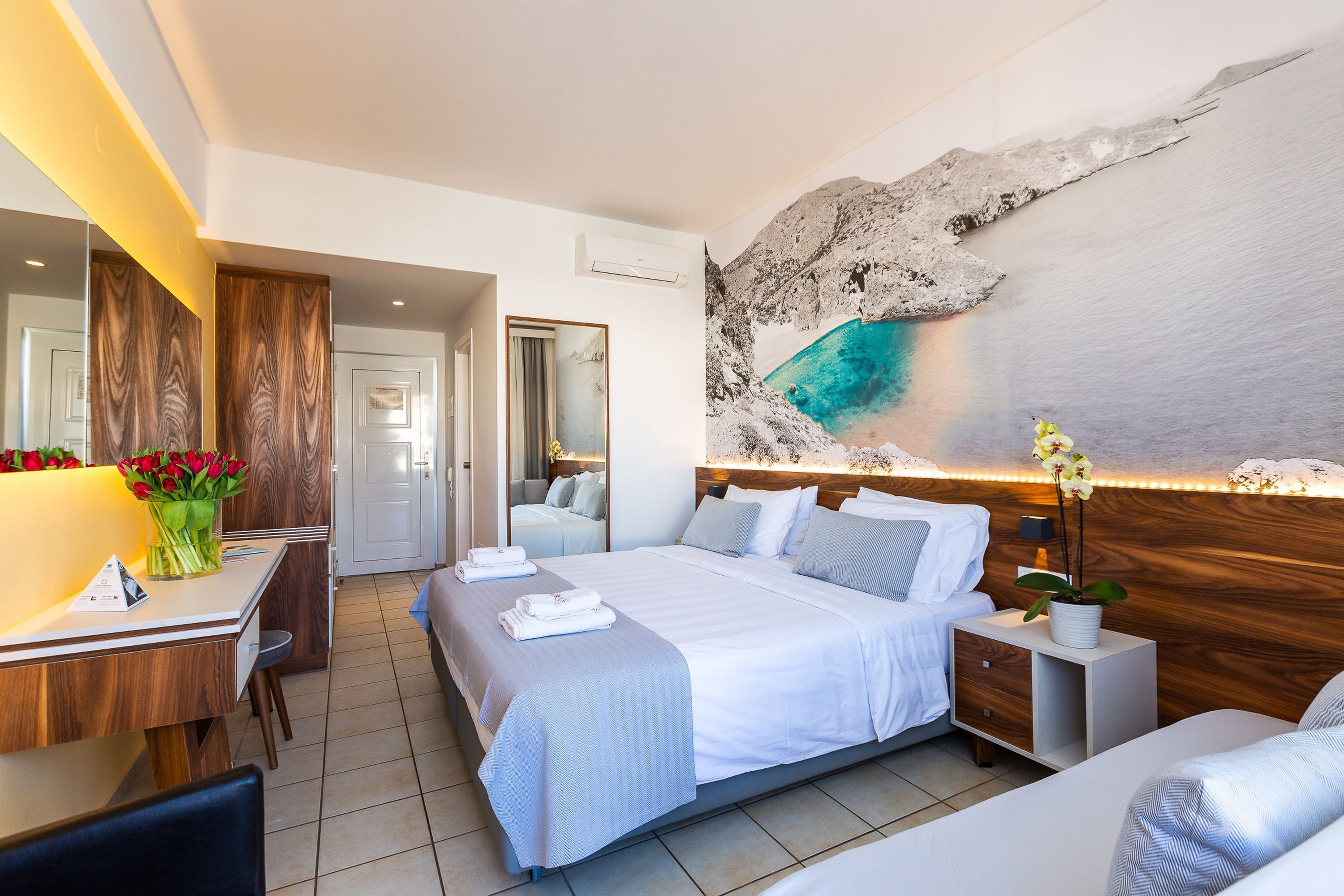 A modern hotel room with a large bed, bedside tables, a desk, and a bathroom.