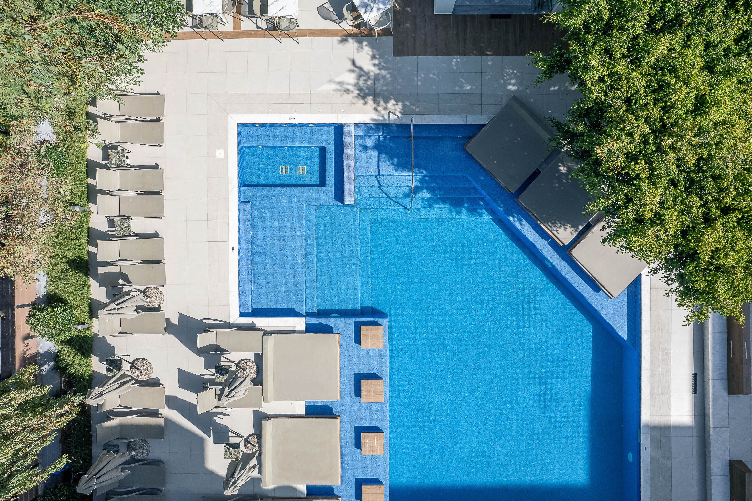 Vue aérienne d’une piscine avec des chaises longues et un petit espace équipé d’un jacuzzi.