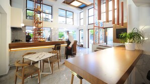 A modern interior with a wooden bar, seating area, and large windows. - Atrium Ambiance Hotel (Rethymno)