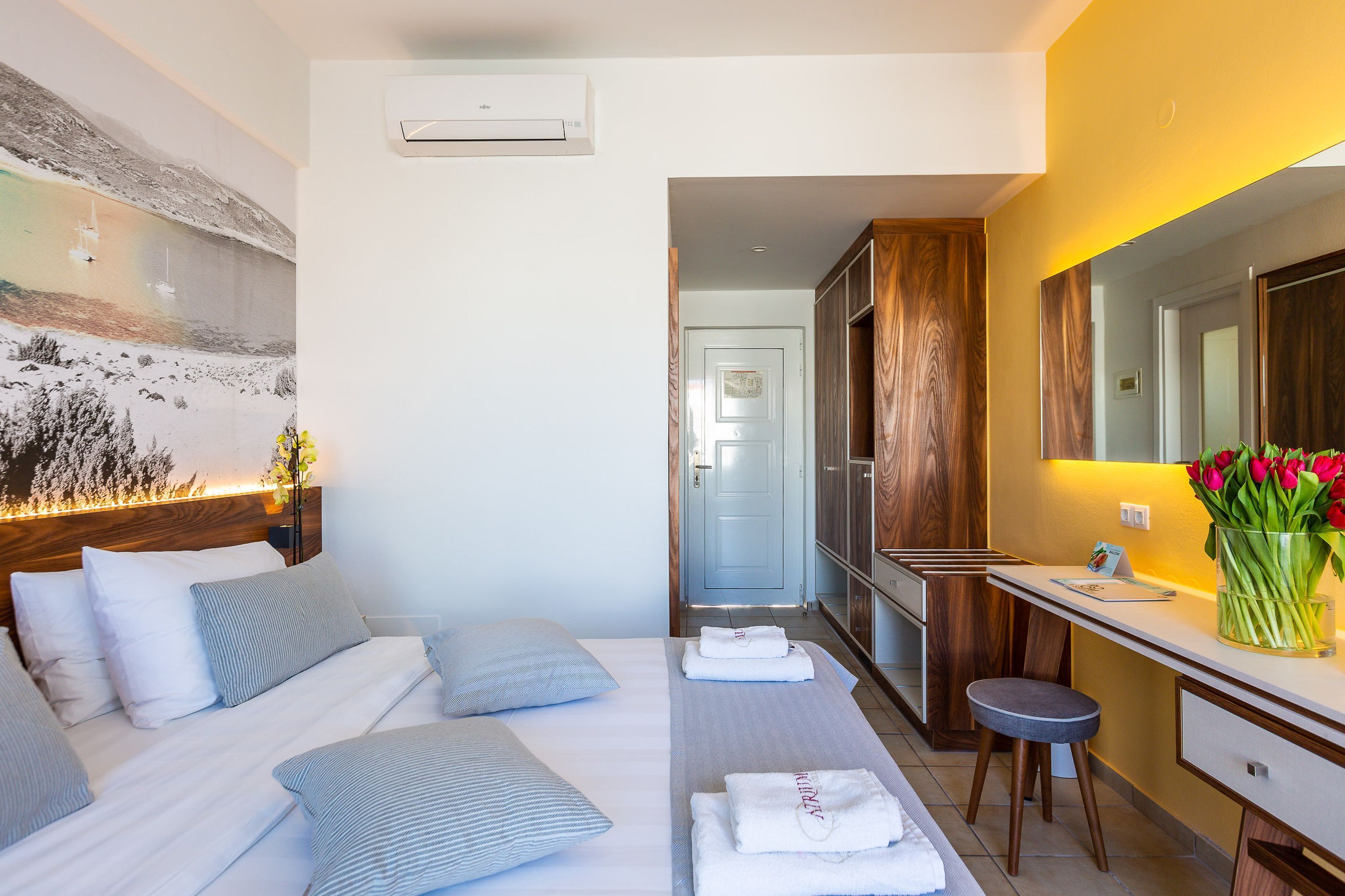 Hotelkamer met een bed, bureau, spiegel en een wandairconditioner.