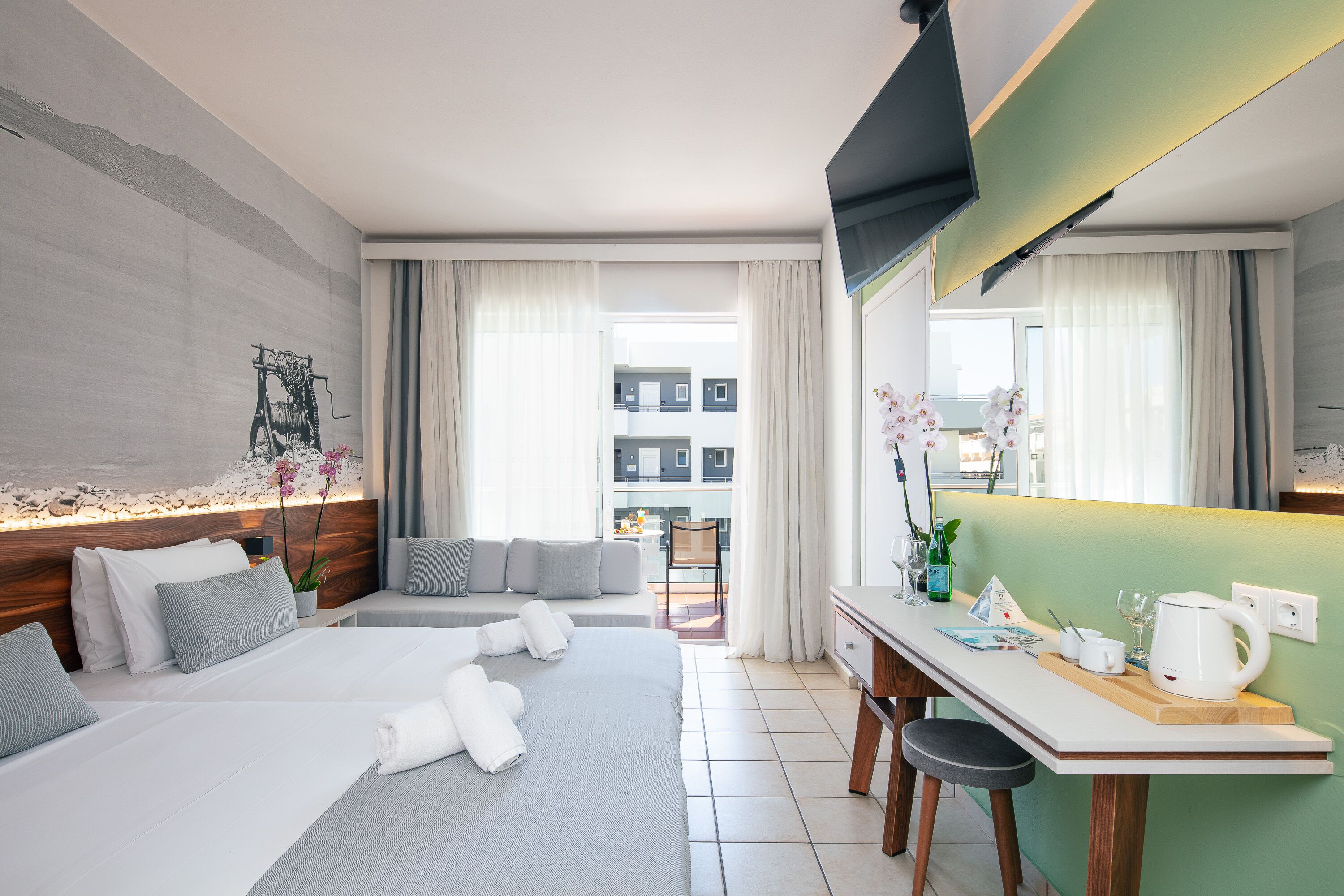 A modern hotel room with a large bed, a desk, and a view of the city.