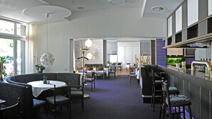 A modern bar area with a counter, seating, and a view of the dining area. - Hotel-Restaurant Thomsen (Delmenhorst)