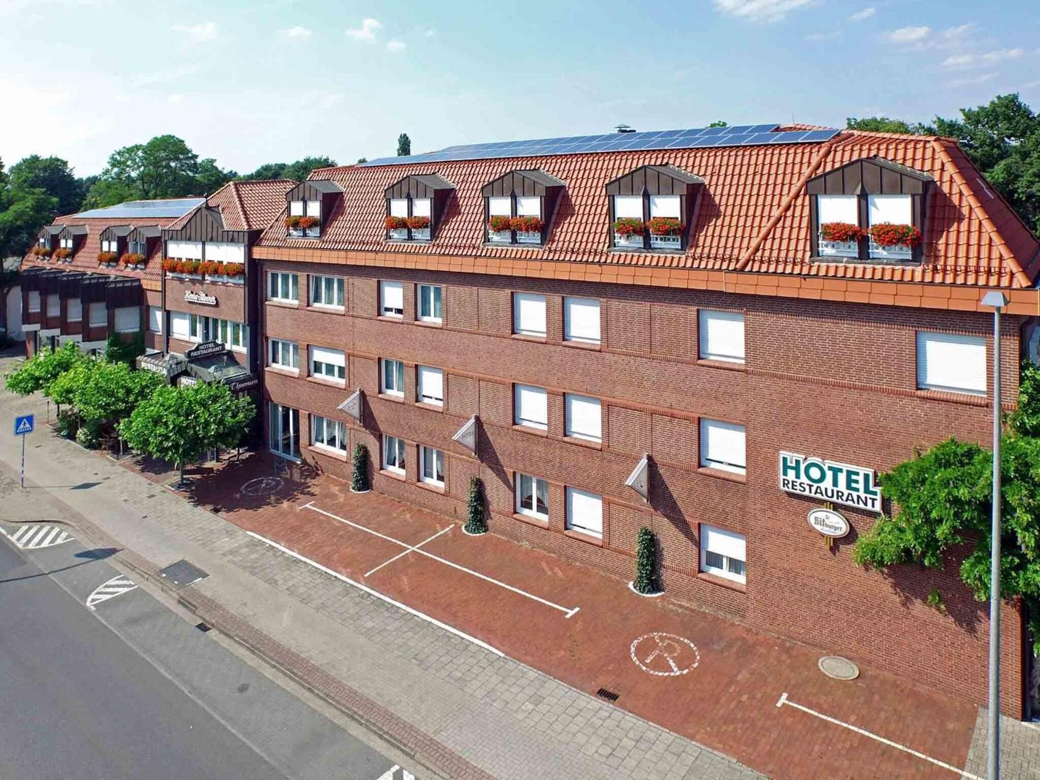 A hotel with a red-tiled roof, multiple windows, and a sign indicating it is a hotel and restaurant.