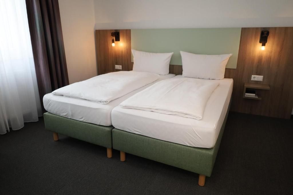 Una cama doble con dos almohadas, una mesita de noche con lámpara y un cabecero de madera.