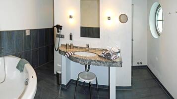 A modern bathroom with a freestanding bathtub, a vanity with a granite countertop, and a mirror above the sink.