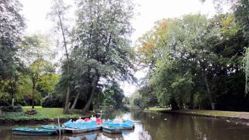 Ein ruhiger Fluss mit vertäuten Booten links, umgeben von dichten Bäumen und üppiger Vegetation.