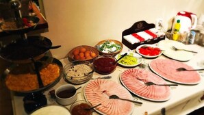 A buffet table with various dishes including meats, fruits, and condiments. - Aparthotel Susa (Prague)
