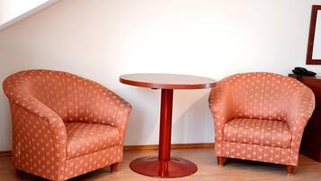 Two armchairs with a leaf pattern, a round wooden table, and a wooden floor.