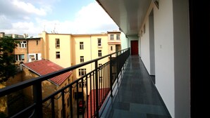 A balcony with a view of adjacent buildings and a red car parked below. - Aparthotel Susa (Prague)