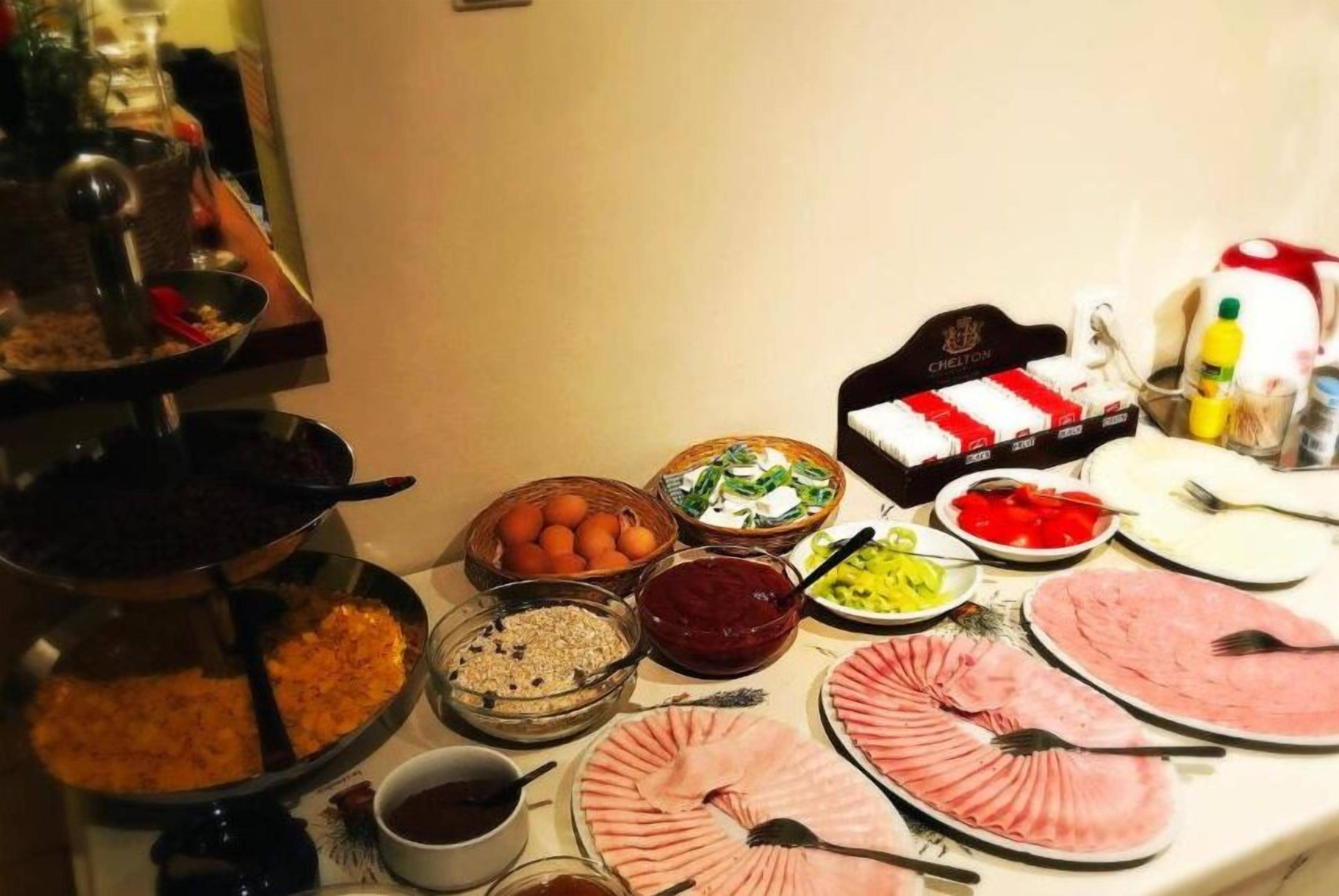 A buffet table with various food items including meats, fruits, and condiments.