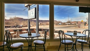 Un restaurante con mesas al aire libre, un cartel que anuncia servicios como piscina climatizada e internet Wi-Fi, y vistas a un paisaje desértico.