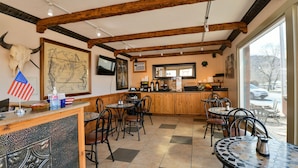 Un restaurante con un interior rústico, con vigas de madera a la vista, una gran decoración de cráneo de toro y vistas a través de la ventana.
