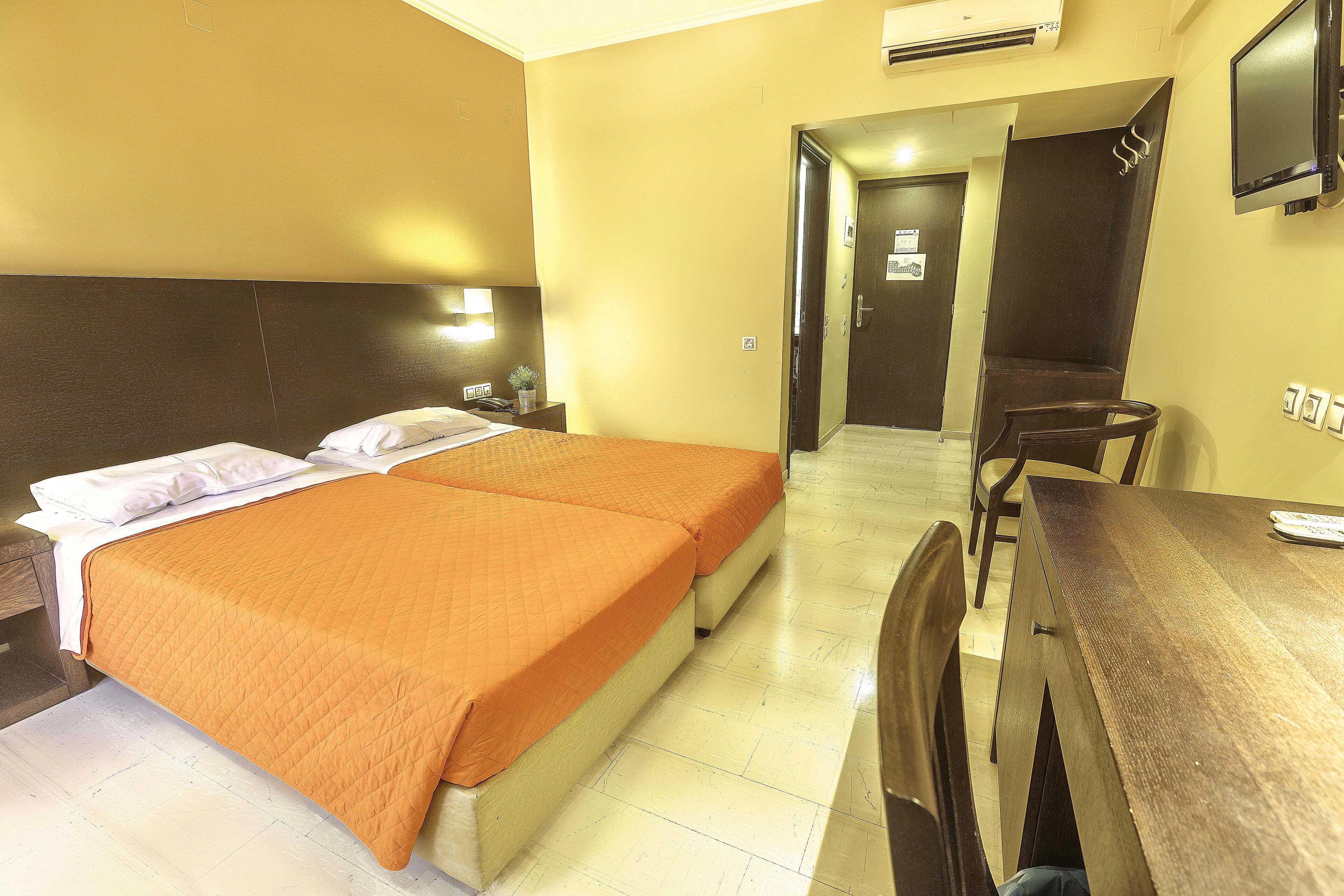 A hotel room with two beds, a wooden table, and a TV.