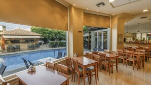 Restaurant amb terrassa a vora d'una piscina, taules i cadires de fusta i vista a la zona de la piscina.