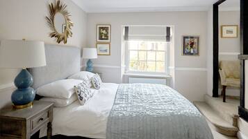 A bedroom with a bed, a nightstand, a lamp, a window, and a chair.