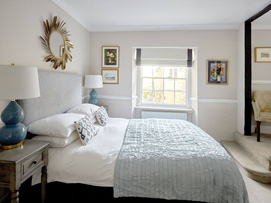 A bedroom with a bed, a nightstand, a lamp, a window, and a chair.