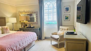 A hotel room with a bed, a desk, a chair, a mirror, and a window with curtains.