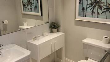 Un bagno con lavandino, mobile lavabo e water bianchi. Ci sono due quadri appesi alla parete, uno sopra il lavandino e uno sopra il water.