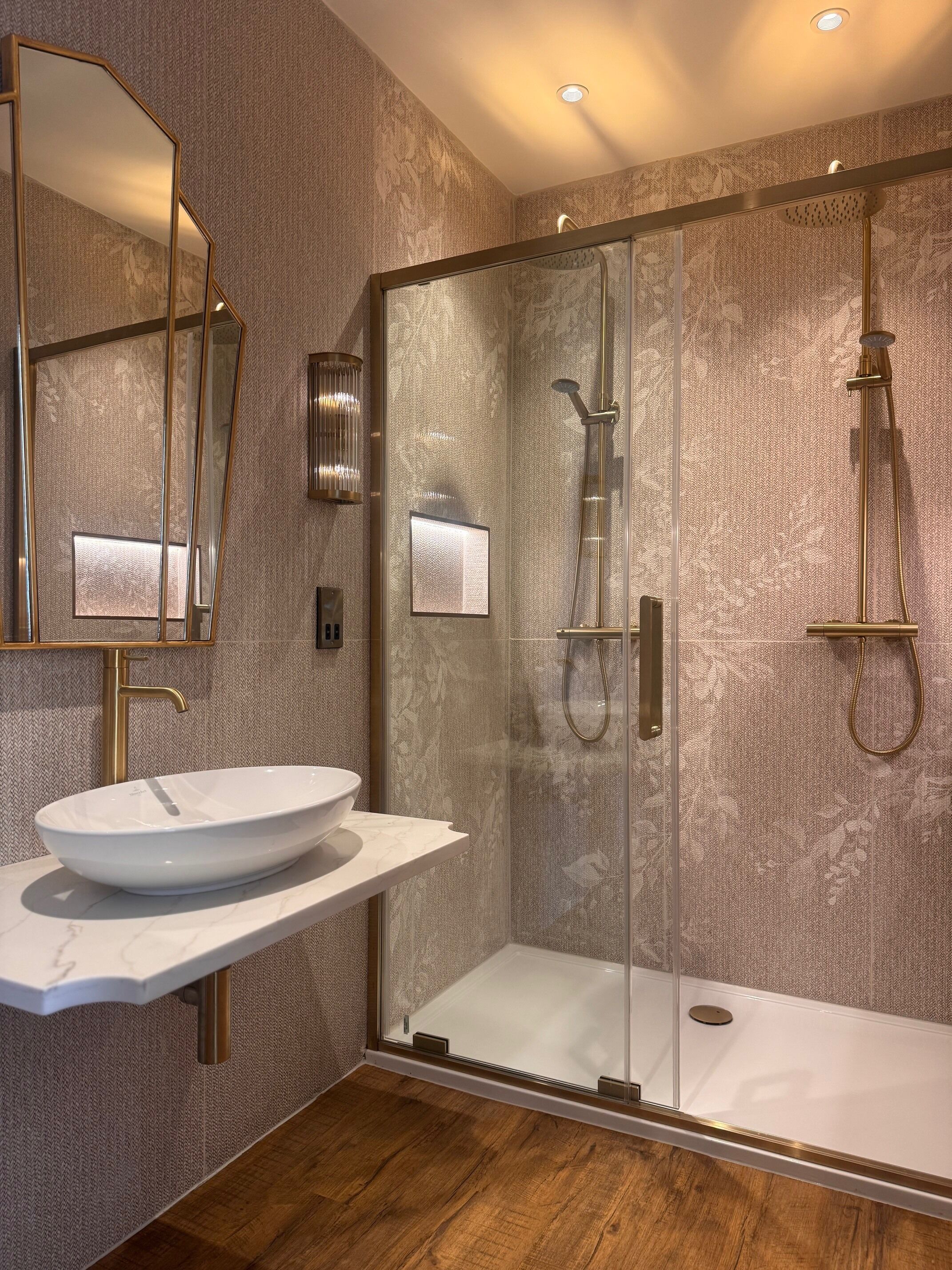Ein modernes Badezimmer mit einer gläsernen Dusche, einem weißen Waschtisch und einem großen Spiegel.