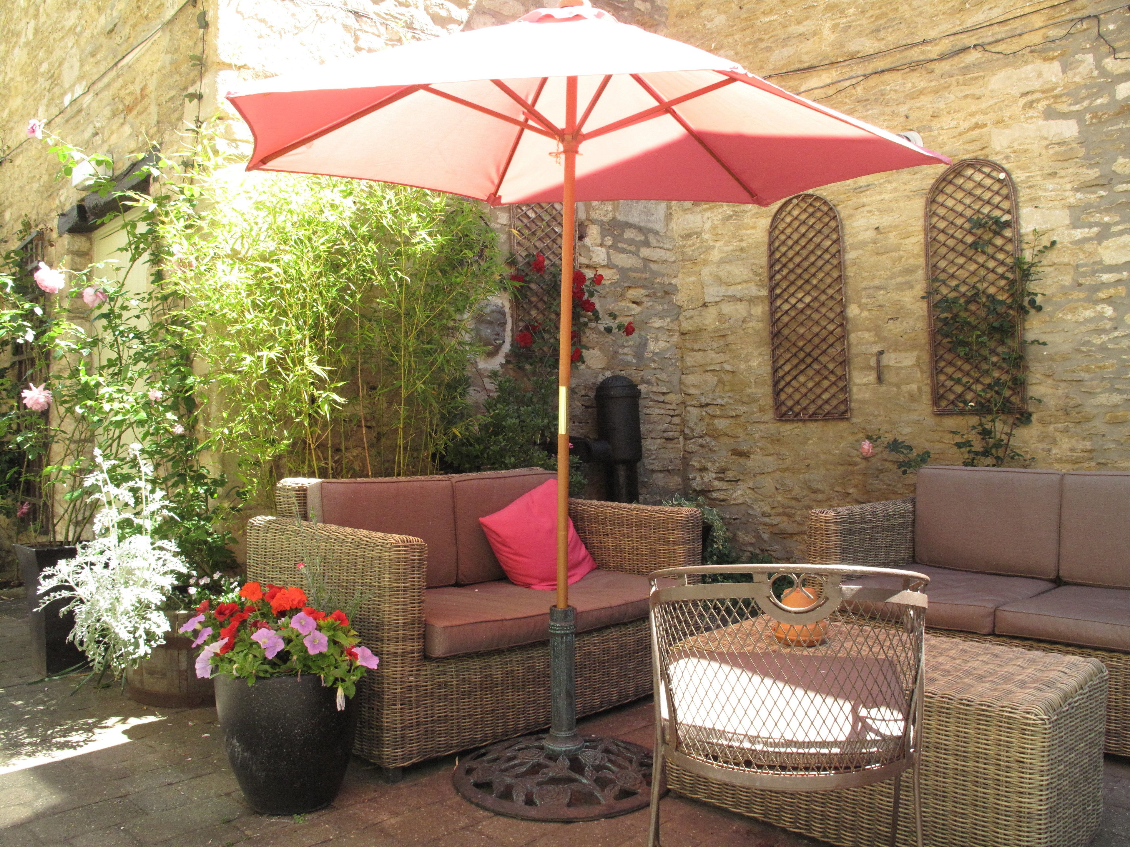 An outdoor seating area with wicker furniture and a red umbrella.
