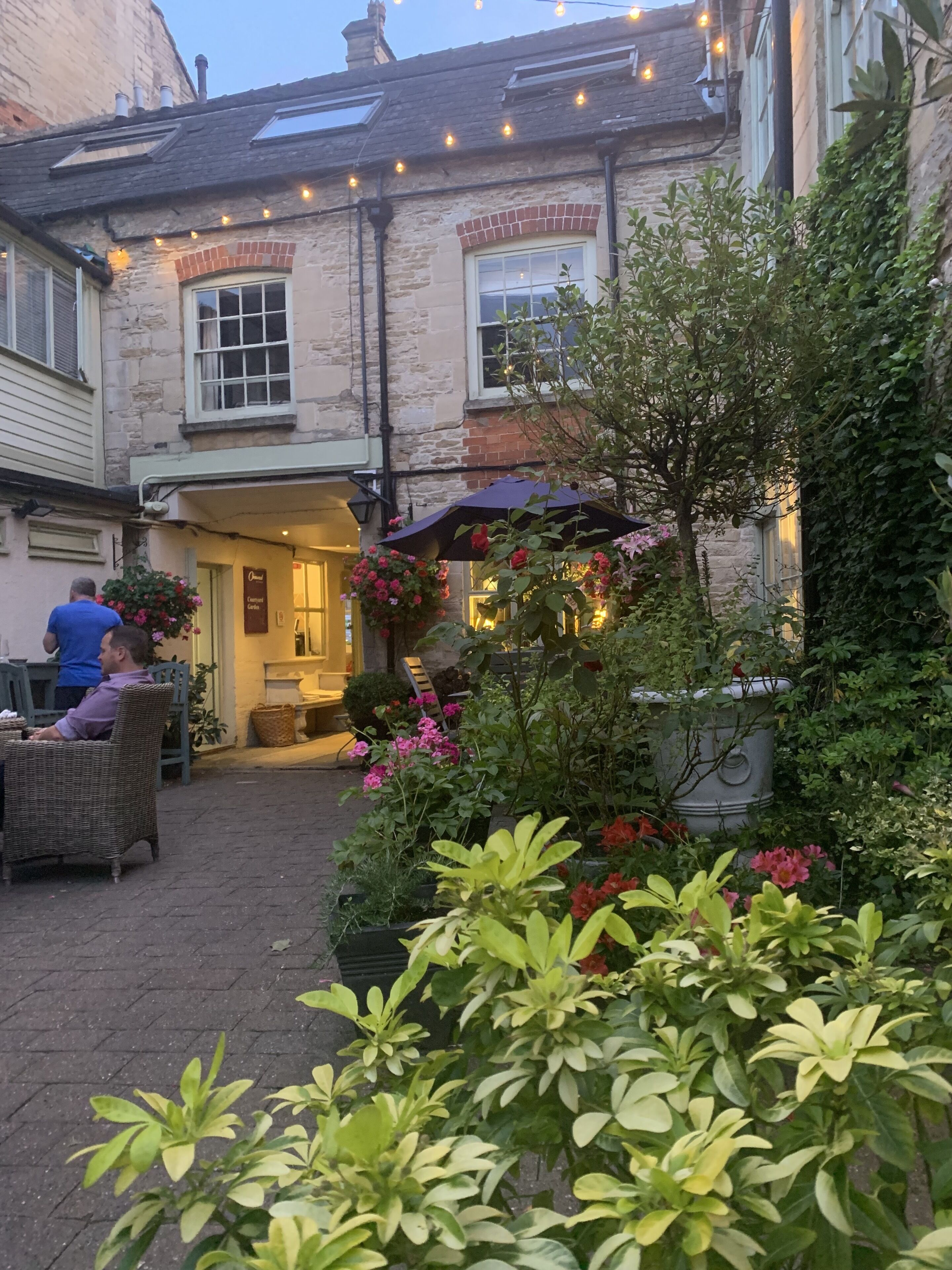 A cozy outdoor seating area with wicker furniture and a flower arrangement in front of a pub named 'Owen's'.
