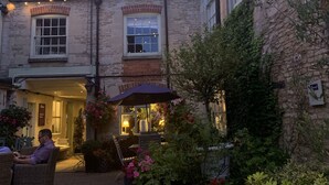 Une cour avec un pub, des tables à l’extérieur et des guirlandes lumineuses.