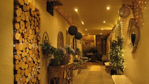 Un couloir étroit, avec un mur fait de rondins de bois d’un côté, un banc et une table au centre.