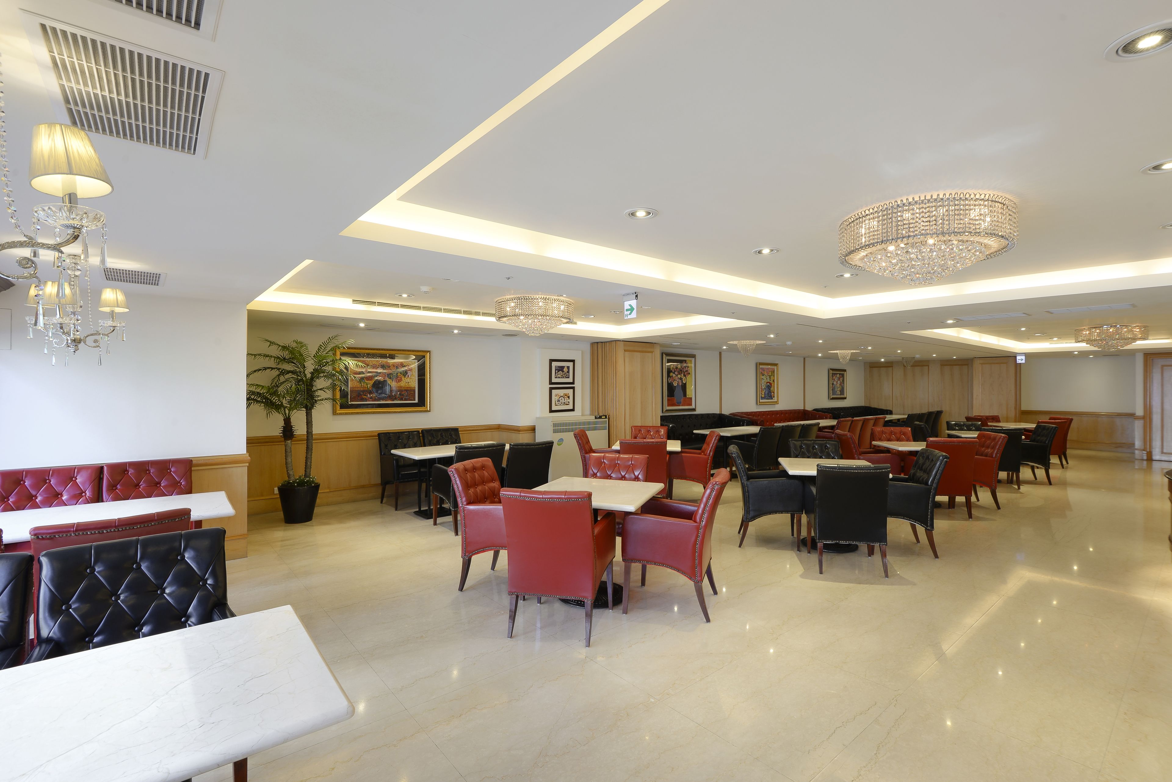 A spacious restaurant with high ceilings, modern chandeliers, and a variety of seating options including booths and tables.