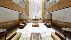 A spacious lobby with a marble floor, wooden paneling, and a central seating area with chairs and a table. - Hotel Sunshine (Kaohsiung)