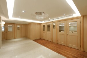 A spacious room with wooden cabinets, a chandelier, and a polished floor.