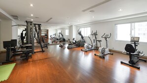 A spacious gym with various exercise machines, a green mat, and a large window providing natural light. - Hotel Sunshine (Kaohsiung)