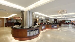 A modern hotel lobby with a central buffet area, wooden paneling, and a chandelier. - Hotel Sunshine (Kaohsiung)