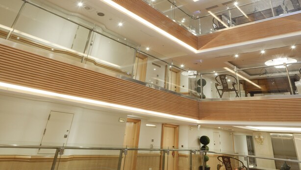 A multi-level atrium with glass railings, wooden paneling, and modern lighting. - Hotel Sunshine (Kaohsiung)