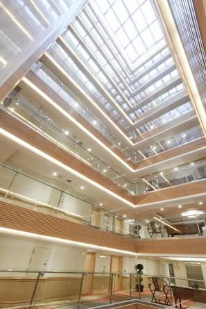 A multi-level atrium with glass railings, wooden paneling, and modern lighting. - Hotel Sunshine (Kaohsiung)