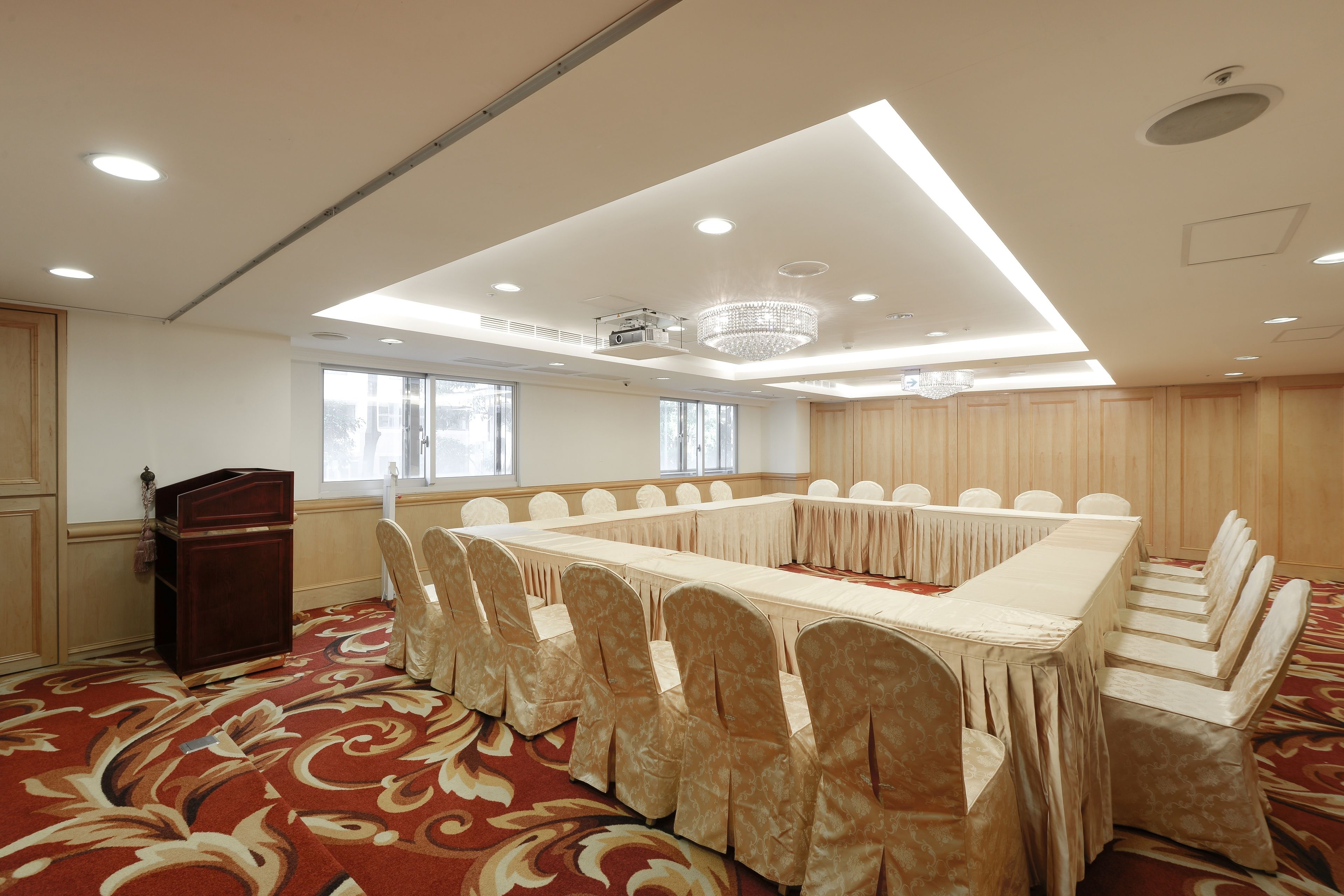 A conference room with a long table and chairs, a podium, and a chandelier.