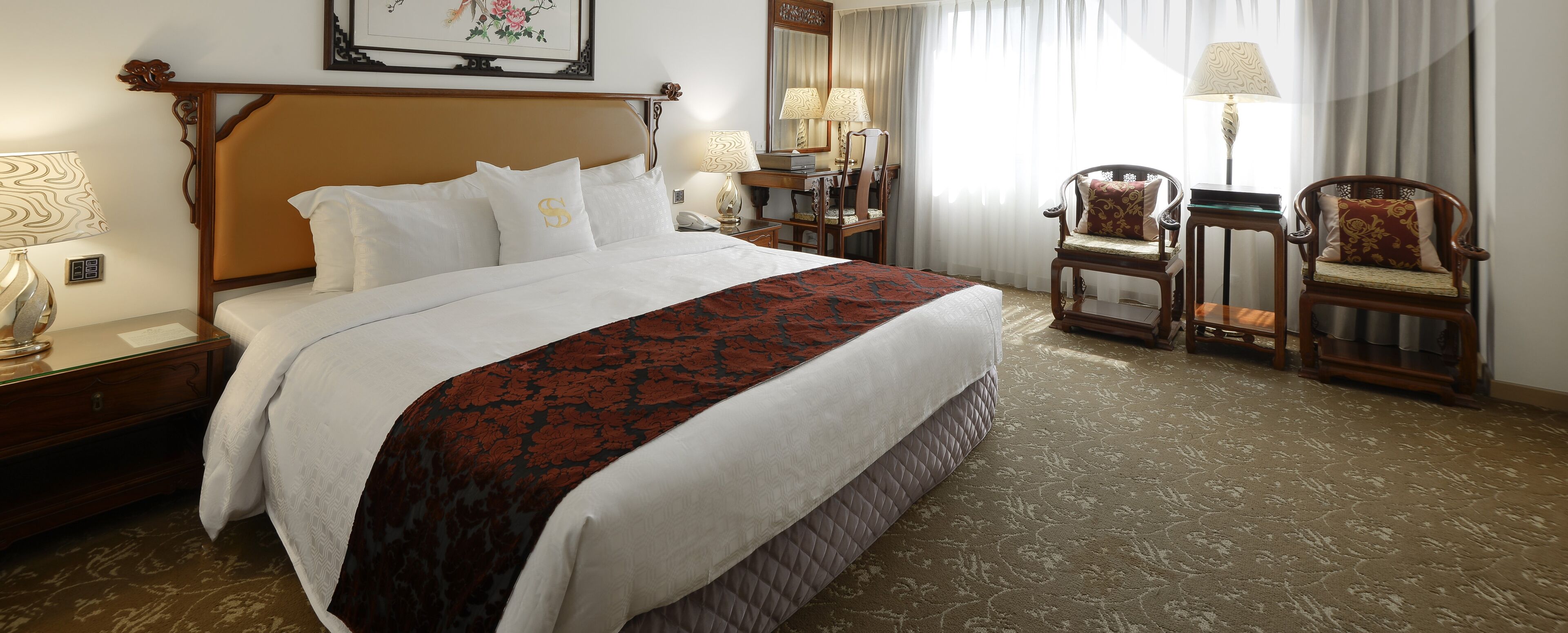 Habitación de hotel con una cama grande, dos sillas, un escritorio y un espejo.