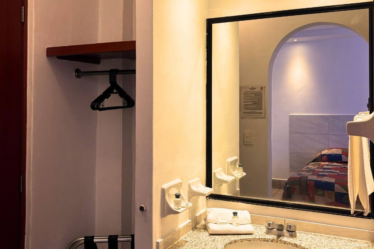 Une salle de bain avec un comptoir en granit, un lavabo, un miroir, un porte-serviettes et une porte.