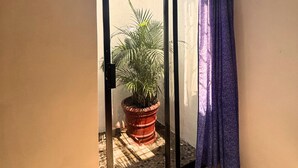 Ein Zimmer mit einer Schiebeglasdoor zu einem Balkon mit einem Blumentopf.