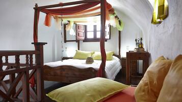 Relax in a cozy retreat with a four-poster bed, adorned with pillows and a woven basket, beneath a draped canopy.