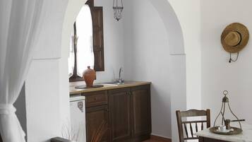 A kitchen with an arched doorway, wooden cabinets, a sink, and a dining area with a table and chairs.