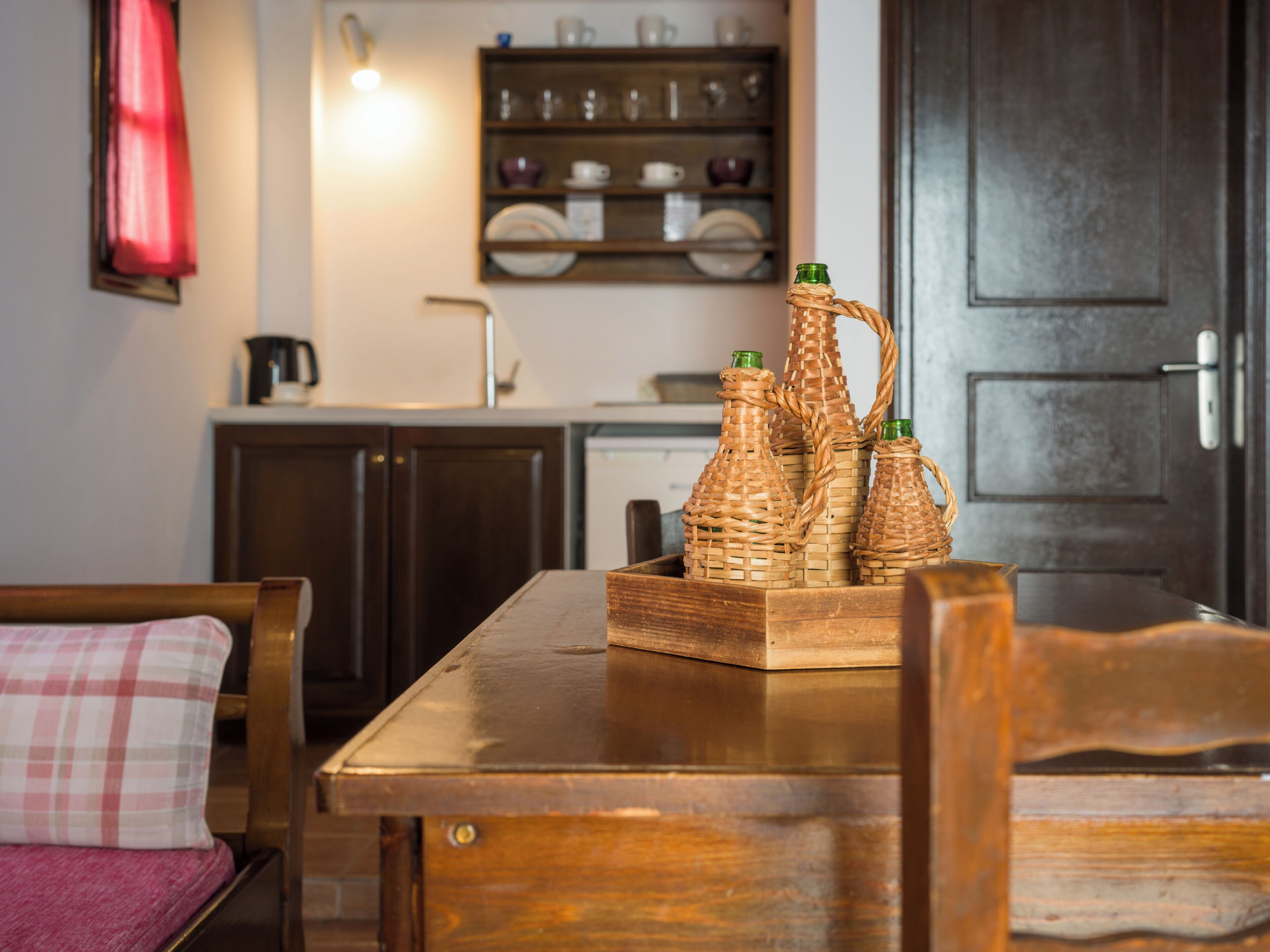 A wooden dining table with a woven basket containing three bottles.