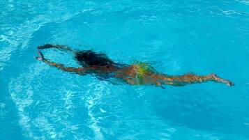A person swimming in a clear blue pool.