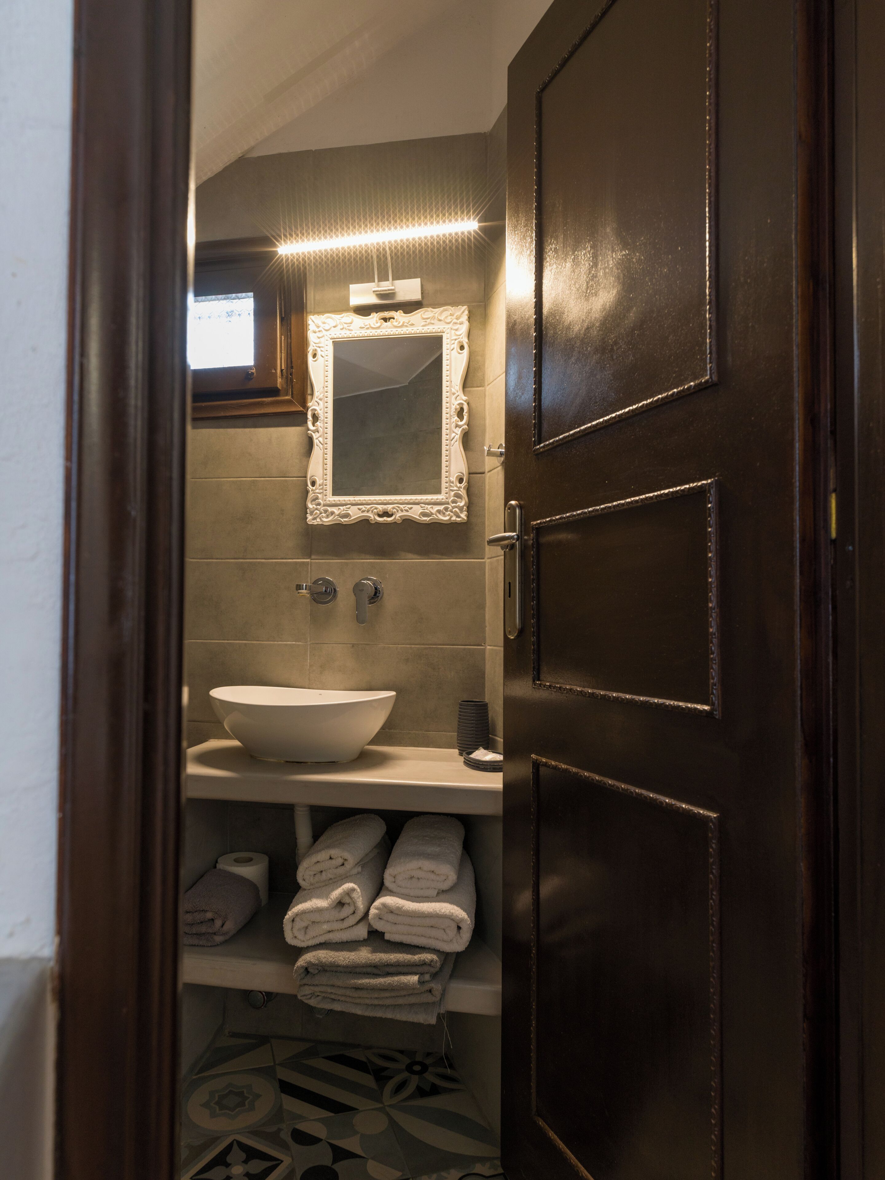A bathroom with a white sink, a mirror, and a towel rack with towels.